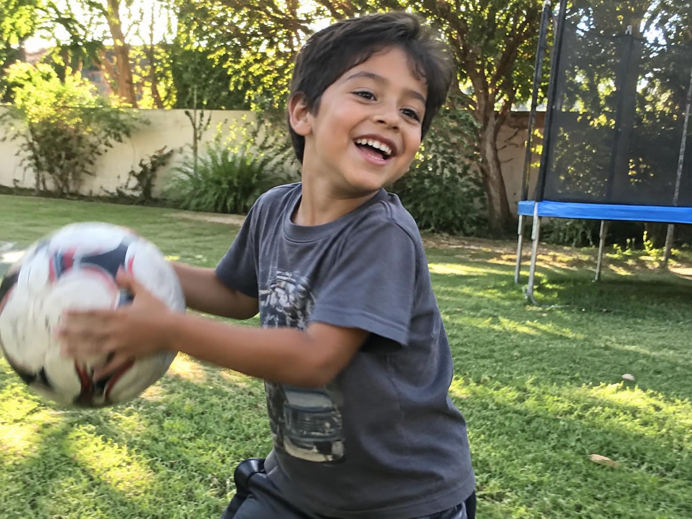Niño jugando feliz con una pelota al aire libre